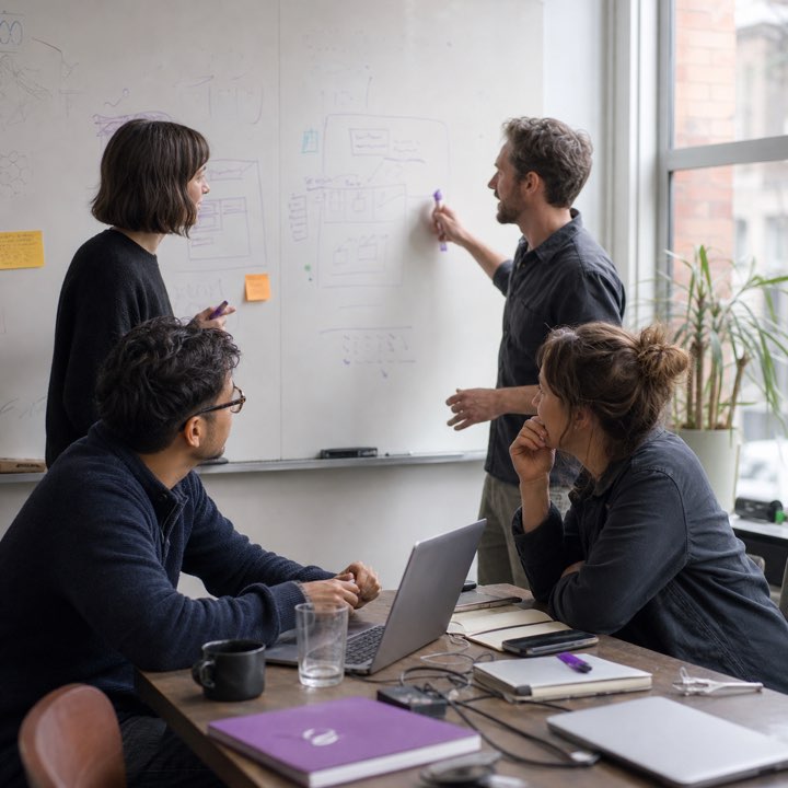 Product and engineering teammates collaborating around a laptop in a bright office